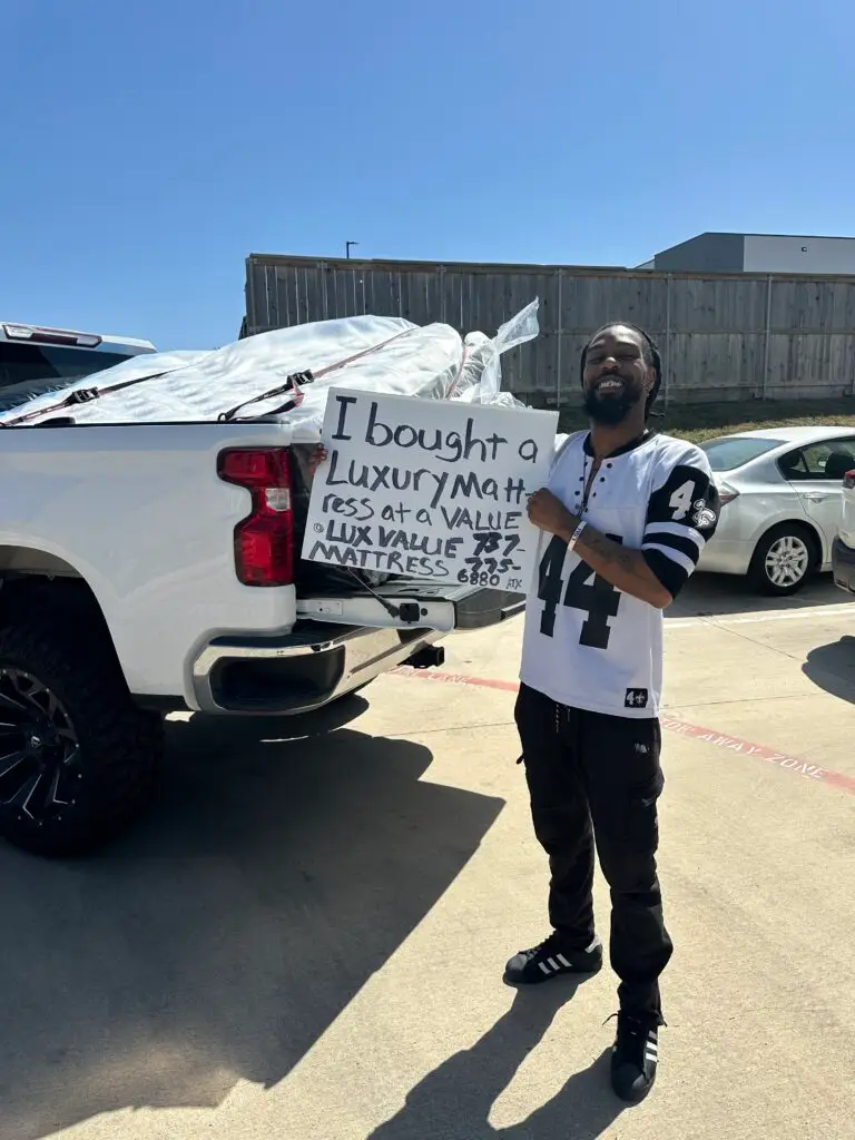 Customer posing outside Lux Value Mattress with showroom purchase sign