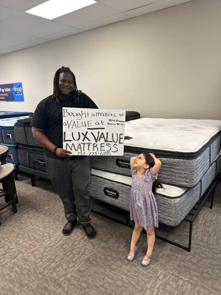 Happy customer holding Lux Value Mattress sign after purchase in Austin showroom