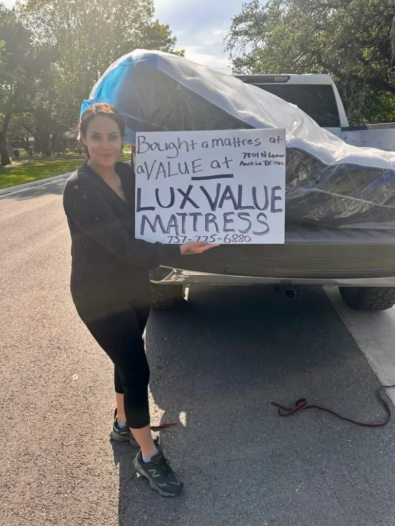 Young woman loading luxury pillowtop mattress at Lux Value Mattress pickup area